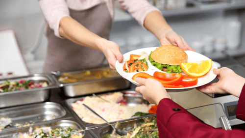 close up of school lunch lady handing tray to student