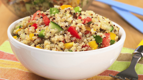 White bowl with quinoa, diced zucchini and tomatoes